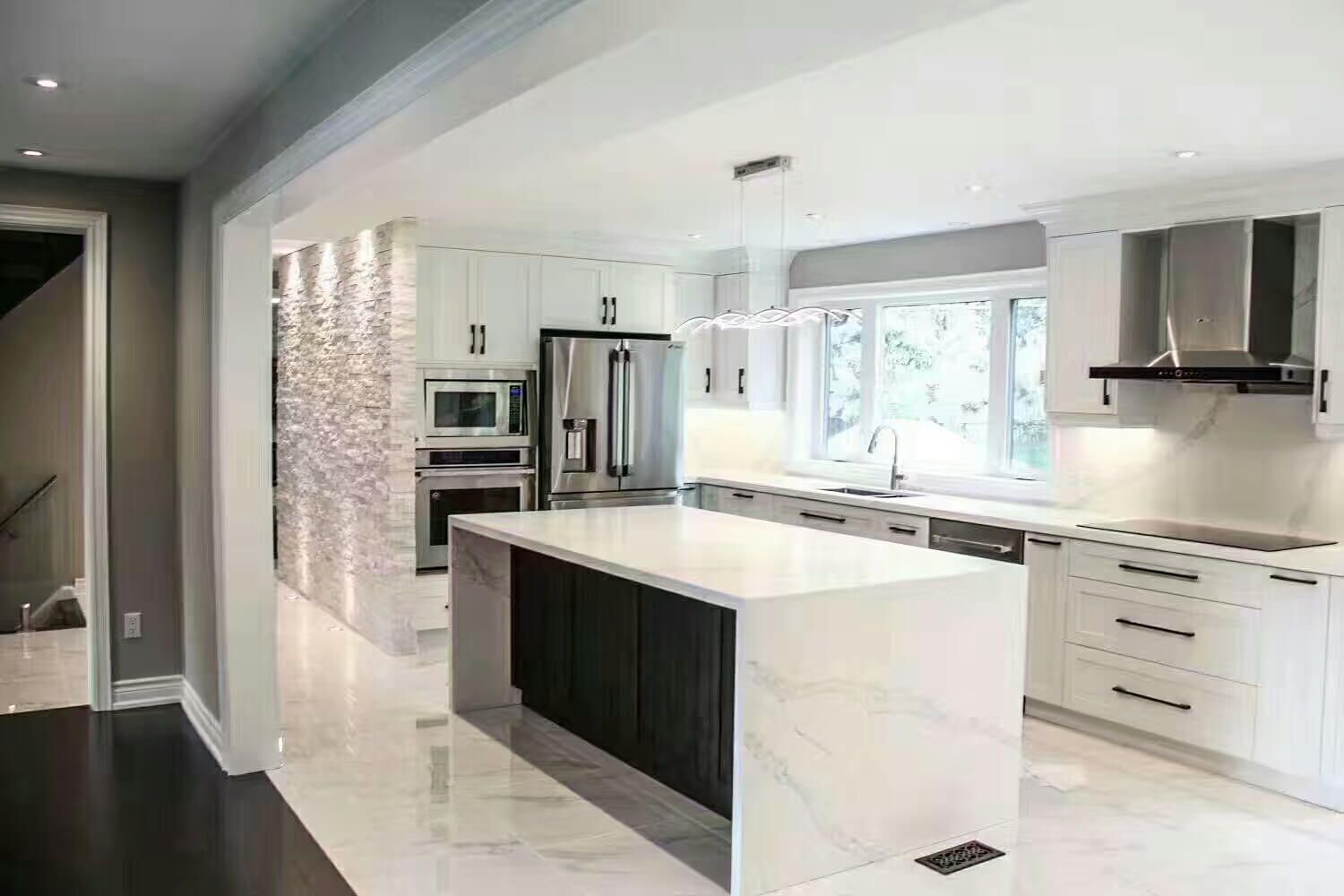 This Markham interior renovation showcases a modern open-concept kitchen featuring a large quartz waterfall island, custom white cabinetry, built-in stainless steel appliances, and elegant pendant lighting. The space combines marble-look flooring with dark wood accents to create a clean, contemporary contrast. Designed for both functionality and style, this Toronto renovation project enhances natural light, improves layout flow, and delivers a bright, luxurious kitchen perfect for modern family living. Completed by a professional Toronto renovation contractor.