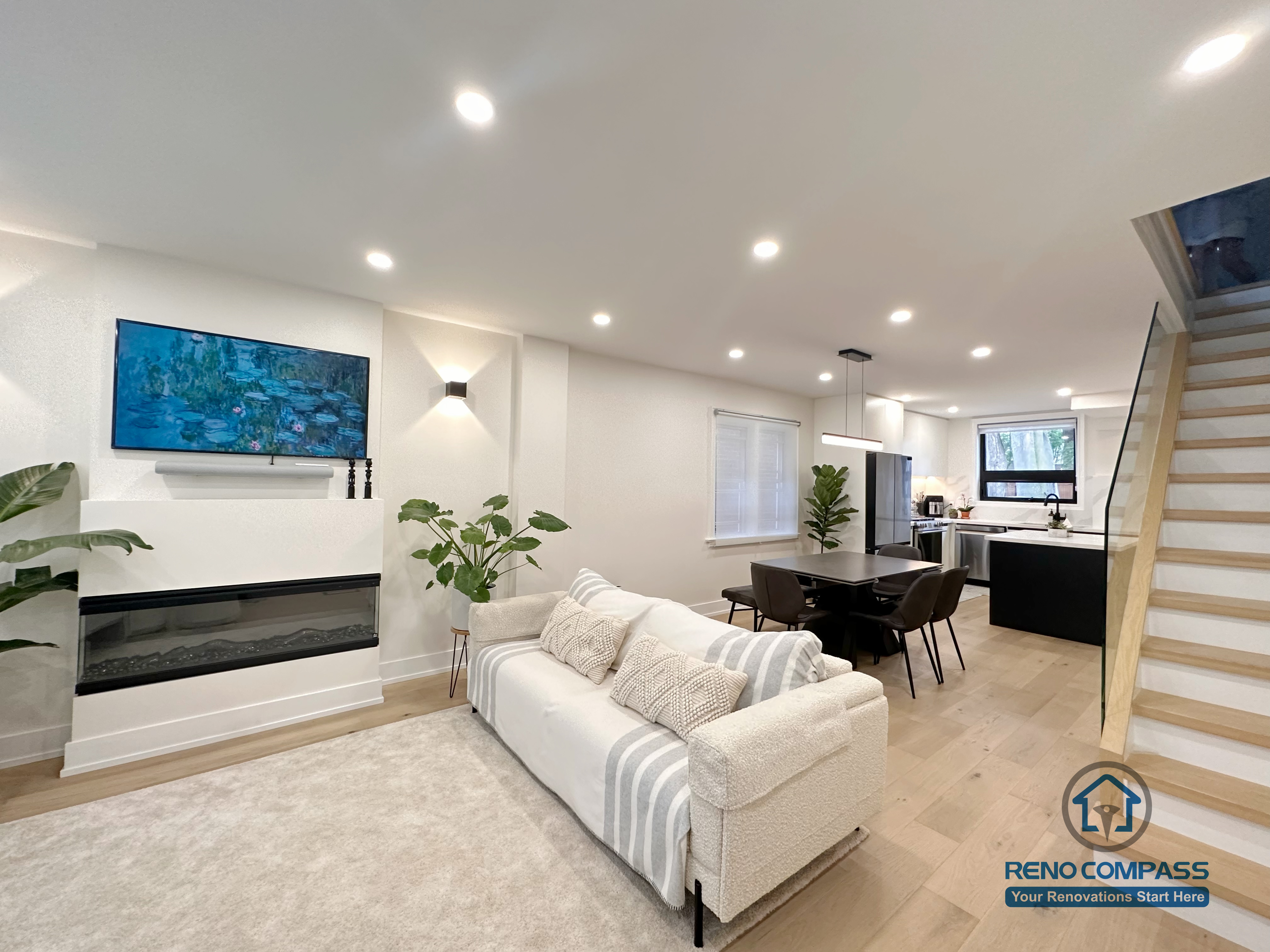 This Toronto interior renovation features a bright modern living room with a built-in linear fireplace, recessed ceiling lighting, wide-plank hardwood flooring, and an open layout connecting the dining and kitchen areas. The balanced design creates a warm yet contemporary living space, completed by a professional Toronto renovation company.