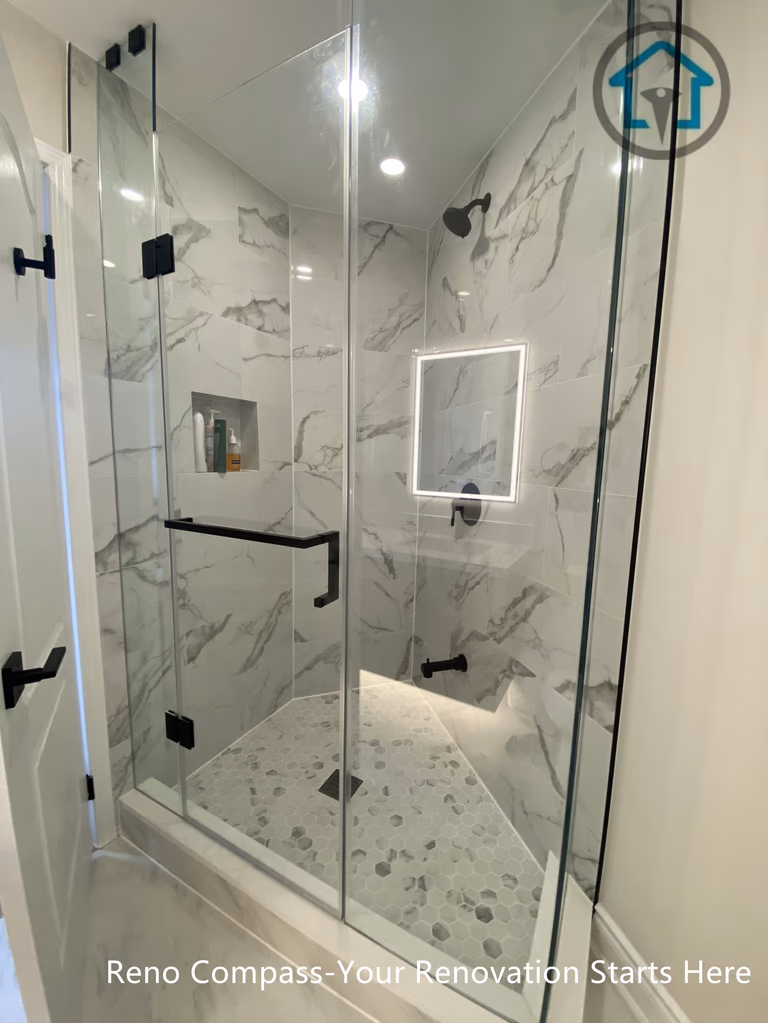 This newly created secondary bathroom in Richmond Hill features a sleek frameless glass shower with marble-style wall tiles and a pebble-finish shower base for a spa-inspired look. Matte black fixtures, recessed niche storage, and soft LED mirror lighting enhance both functionality and modern aesthetics. As part of a one-bathroom-to-two conversion, this upgrade maximizes space efficiency and home value, completed by a professional Toronto renovation company with attention to detail and quality craftsmanship.