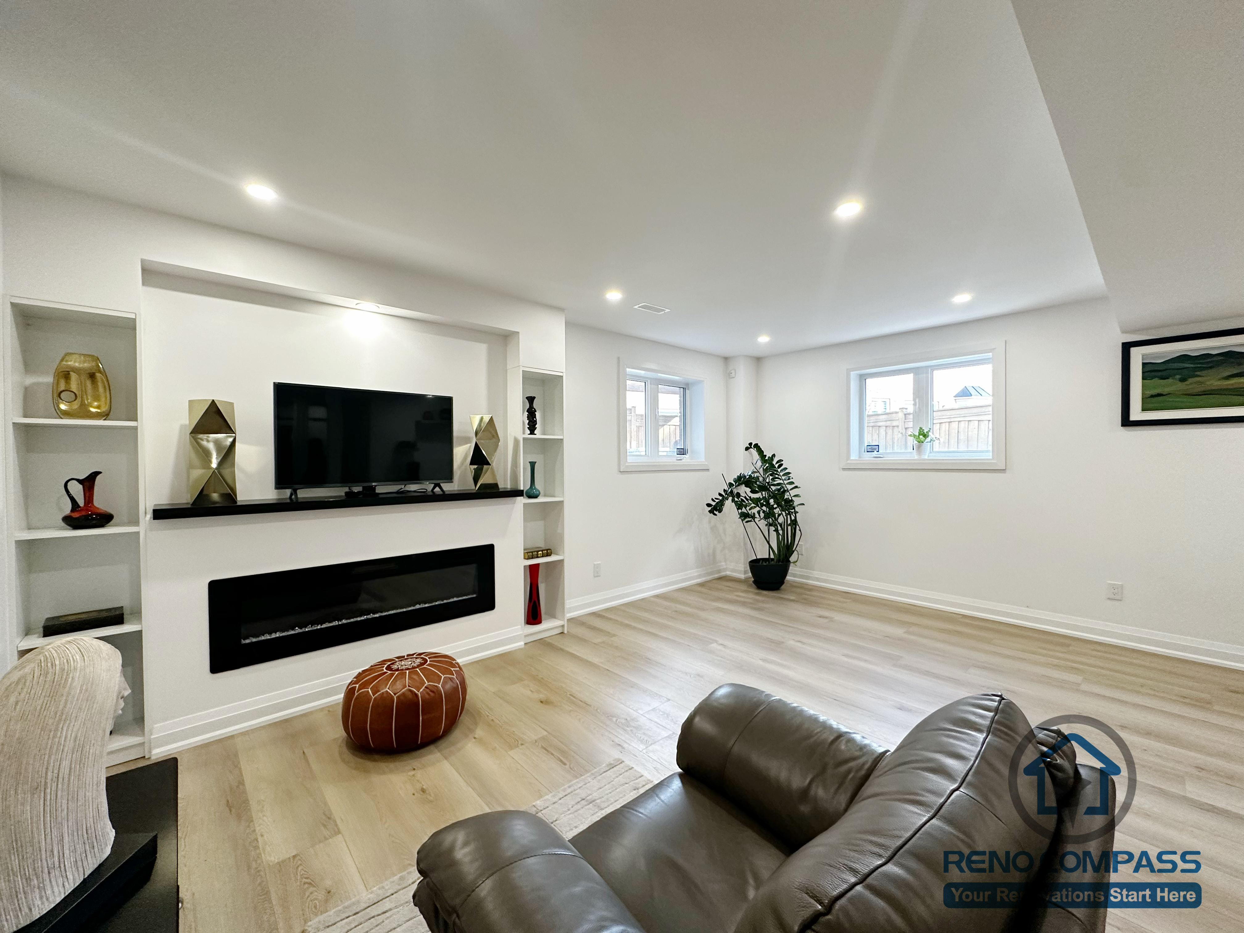This Richmond Hill basement renovation showcases a finished family living space designed for comfort and everyday use. The layout features a custom built-in media wall with a linear fireplace, integrated shelving, and recessed lighting for even illumination throughout the space. Wide-plank flooring suitable for basement conditions is paired with a clean wall finish and well-positioned windows to support a bright, welcoming environment. The open layout allows flexible furniture placement, making the basement ideal for family gatherings, relaxation, or entertainment.