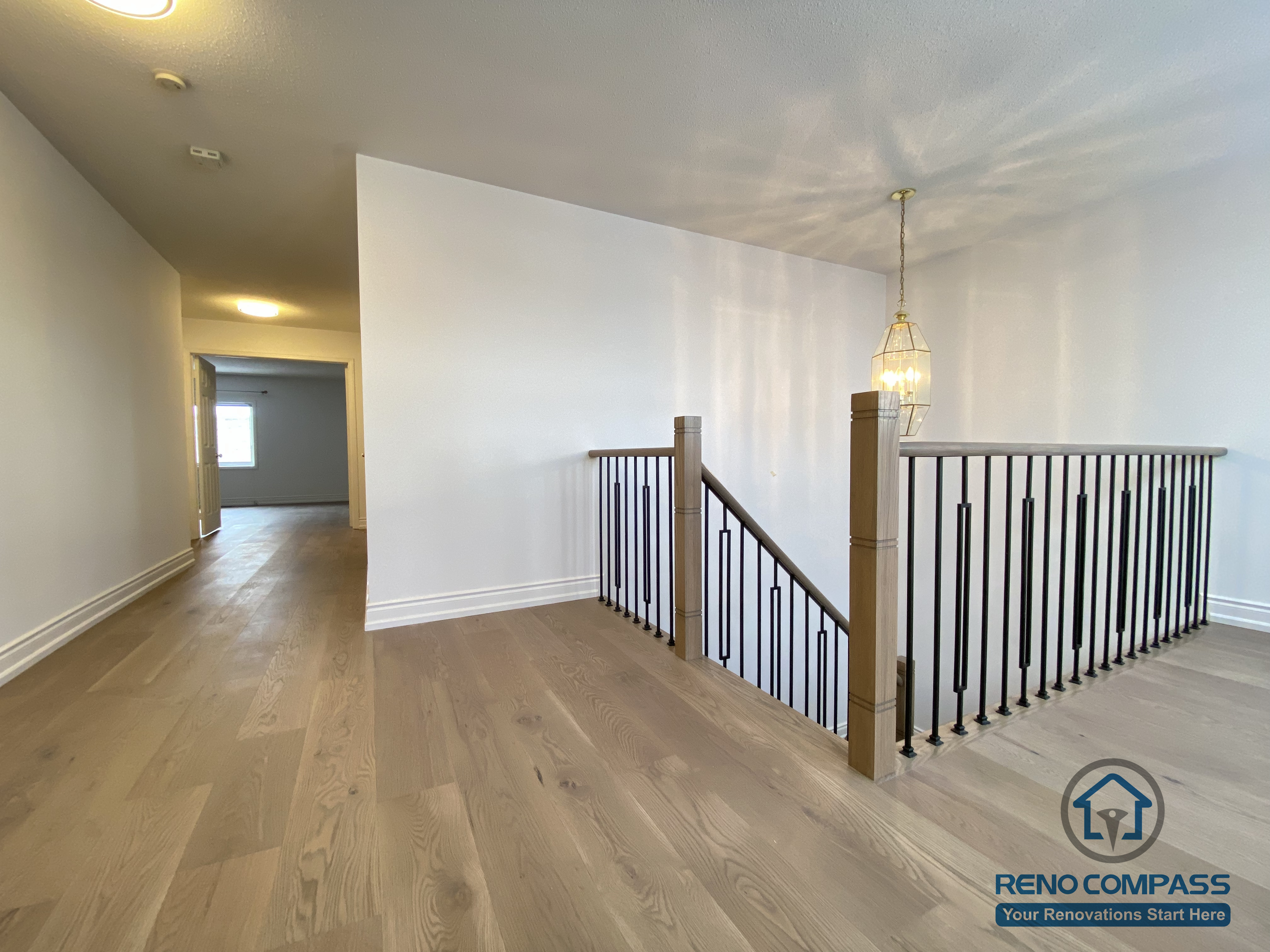 This staircase renovation in Markham showcases a refined transition space featuring custom black iron railings paired with engineered hardwood flooring. Clean vertical balusters and a solid wood handrail enhance safety while maintaining an open, modern visual connection between levels. The upper landing is finished with warm-toned hardwood, creating continuity with the rest of the home’s flooring and improving overall flow. Completed by a trusted Toronto renovation company, this staircase upgrade emphasizes proportion, durability, and timeless interior design suitable for long-term family living.