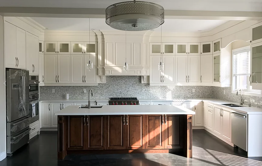 This modern Markham kitchen renovation features custom white cabinetry, a large central island with dark wood base, quartz countertops, and built-in stainless steel appliances. Elegant mosaic backsplash, detailed crown molding, and pendant lighting create a bright and luxurious cooking space. Completed by a professional Toronto renovation company, this kitchen combines functionality, storage, and timeless design for modern family living.