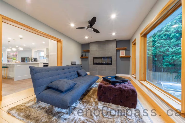 This family room is part of a North York interior renovation, designed to create a warm and inviting space for everyday living and relaxation. The room features a modern built-in fireplace wall, recessed ceiling lighting, and a ceiling fan for comfort and airflow. Large picture windows and a full-height glass door bring in abundant natural light and connect the interior to the backyard. Thoughtful layout planning, natural wood finishes, and clean modern details reflect the quality and functionality expected from professional Toronto interior renovation projects.
