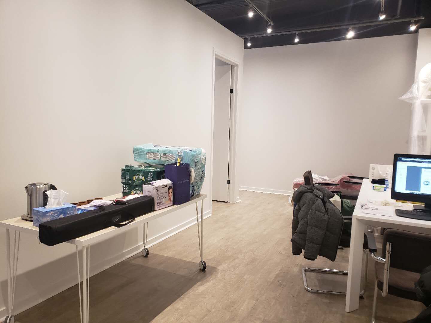 This image highlights the reception and consultation area of a modern beauty and massage spa, completed by a professional Toronto renovation company specializing in commercial interior renovations. The space features clean wall finishes, wood-look flooring, and an open ceiling concept with track lighting to create a contemporary and welcoming environment. Functional workspace planning allows for efficient client check-in, consultation, and daily operations. The minimalist layout and neutral tones enhance the overall calm and professional atmosphere, making it ideal for spa, wellness, and beauty clinic interiors across Toronto and the GTA.