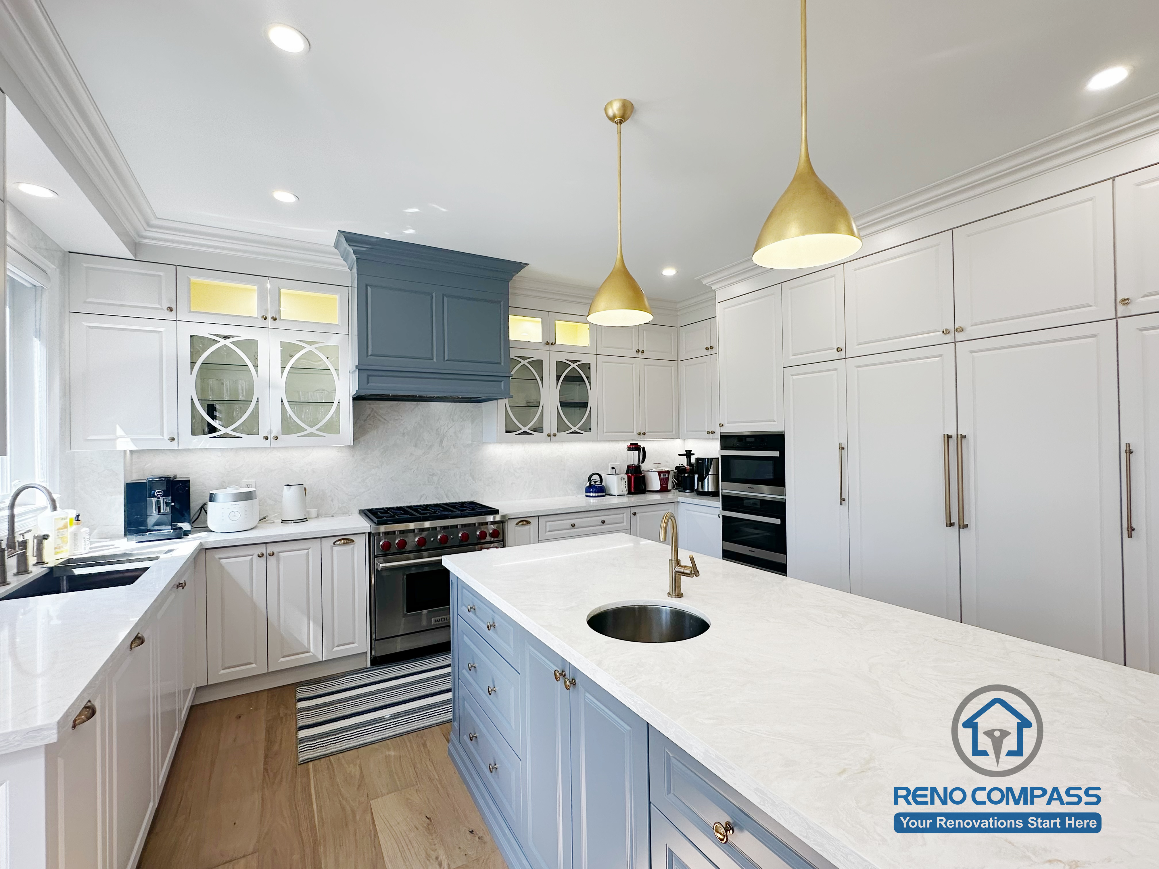 This North York kitchen renovation highlights a custom blue island with integrated drawers, full-height built-in cabinetry, and balanced recessed and pendant lighting. The layout maximizes storage efficiency while maintaining clean lines and visual symmetry, creating a refined and highly functional kitchen space designed and built by Reno Compass.