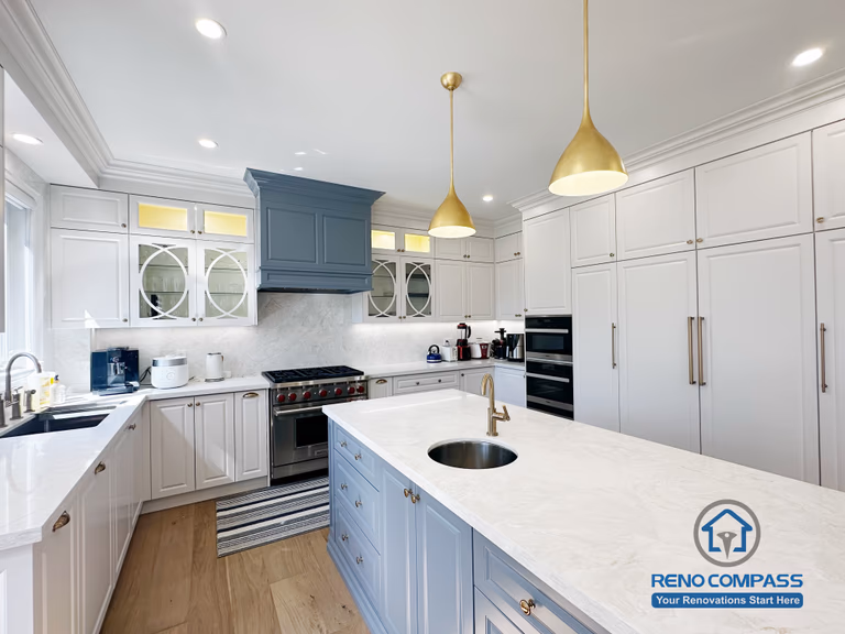 This North York kitchen renovation highlights a custom blue island with integrated drawers, full-height built-in cabinetry, and balanced recessed and pendant lighting. The layout maximizes storage efficiency while maintaining clean lines and visual symmetry, creating a refined and highly functional kitchen space designed and built by Reno Compass.