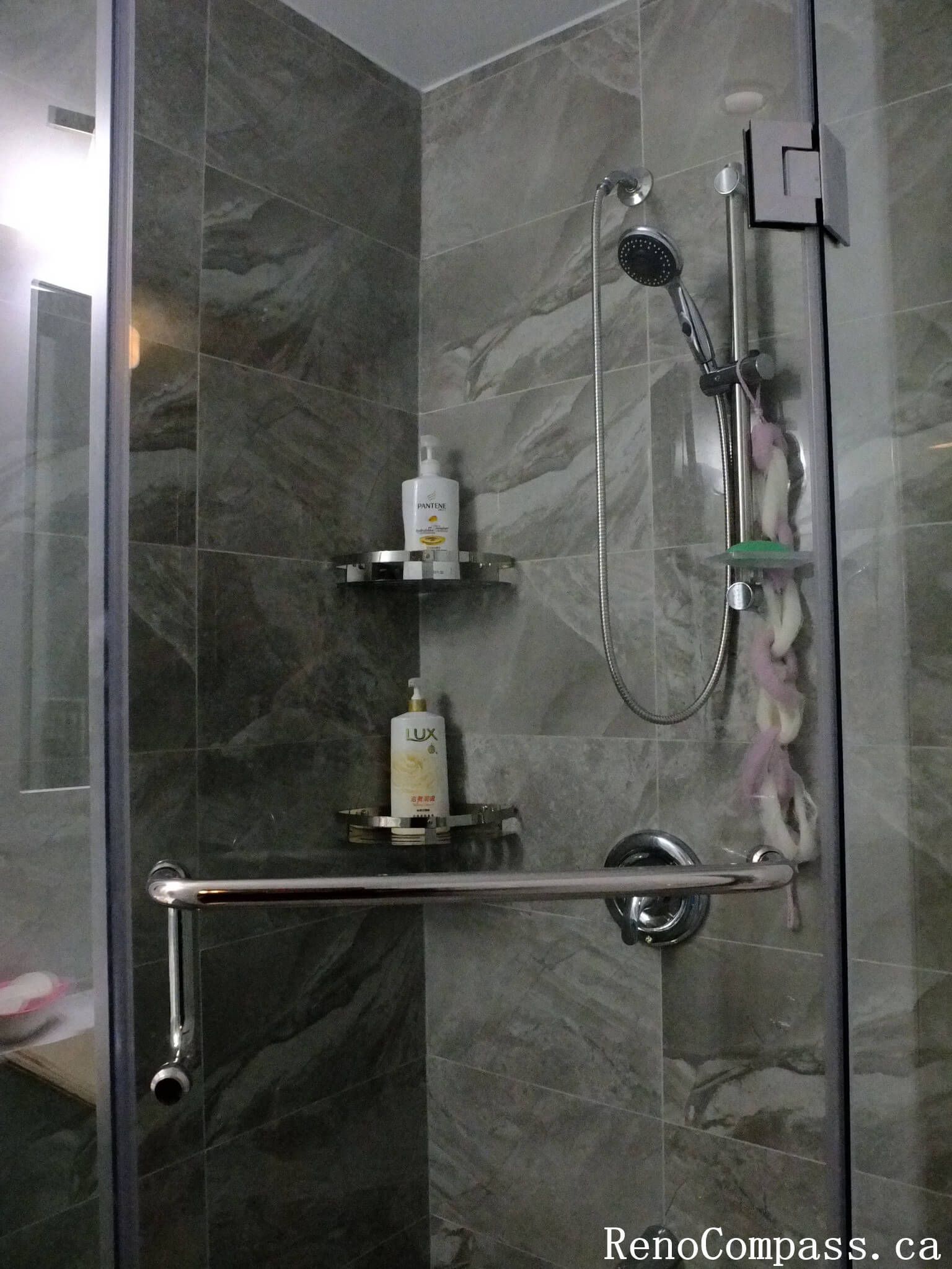 Bathroom interior renovation in North York featuring a frameless glass shower, marble-look porcelain tiles, built-in shower shelf, and modern chrome fixtures. This Toronto interior renovation emphasizes clean lines, functional storage, and durable materials for everyday residential use.
