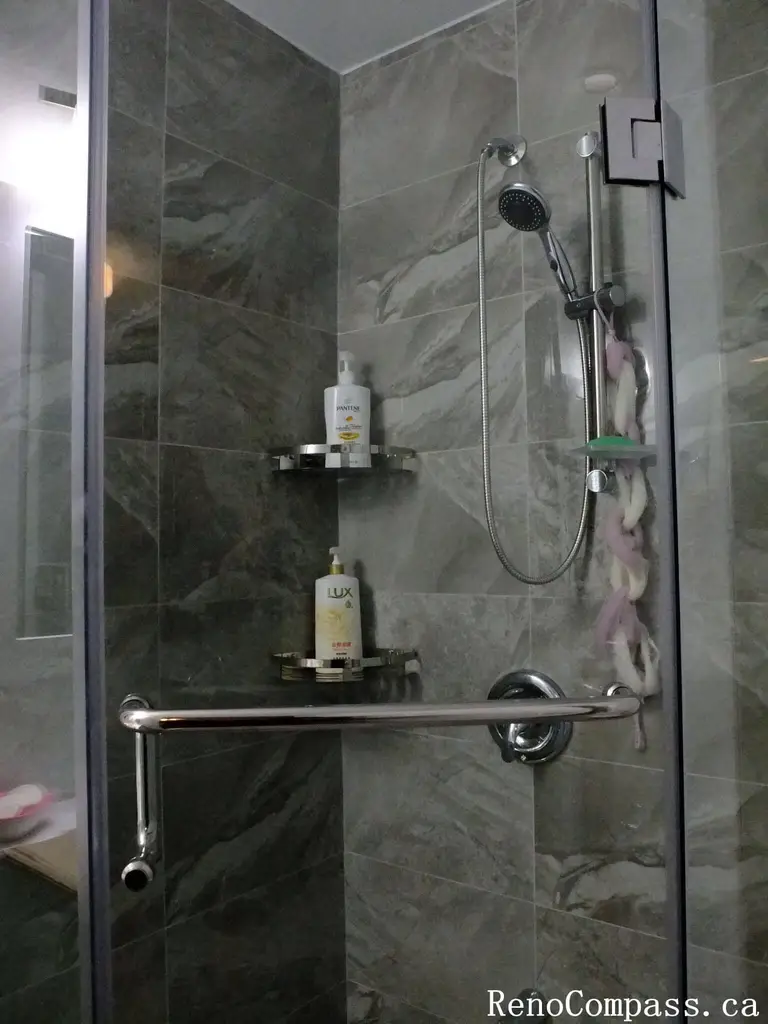 Bathroom interior renovation in North York featuring a frameless glass shower, marble-look porcelain tiles, built-in shower shelf, and modern chrome fixtures. This Toronto interior renovation emphasizes clean lines, functional storage, and durable materials for everyday residential use.