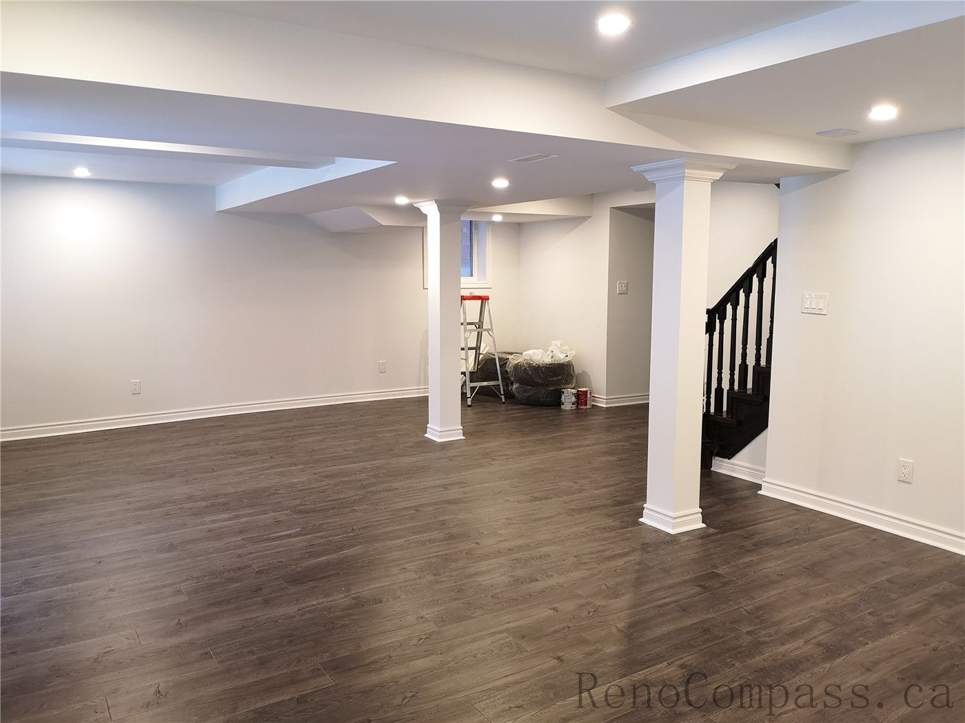 This Richmond Hill basement renovation showcases a spacious open-concept layout with newly installed dark wood flooring, pot lights, and clean modern finishes. Structural columns were integrated seamlessly into the design to maintain an open and functional living space. The upgraded lighting and neutral wall tones create a warm and inviting basement environment ideal for family use or entertainment. Completed by a professional Toronto renovation company, Reno Compass Inc., this finished basement delivers both comfort and contemporary style.