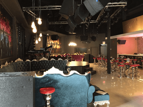 This image showcases the completed lounge area of a 7000 sqft private club renovation project in Toronto. The space features custom velvet sofas with gold trim details, elevated stage setup, professional lighting truss system, and a spacious entertainment layout designed for private events and nightlife experiences.

The open-concept floor plan integrates lounge seating, bar-height tables, and performance areas, creating a refined yet dynamic atmosphere. High ceilings, industrial-style lighting, and polished flooring enhance the sense of scale and sophistication.

Completed by a professional Toronto renovation team, this project demonstrates expertise in large-scale commercial interior construction, combining luxury aesthetics with functional entertainment space planning.

该图片展示多伦多7000尺私人俱乐部装修项目完成后的大厅空间。整体设计采用定制绒面金边卡座、舞台区域及专业灯光吊架系统，打造高端娱乐会所氛围。

开放式布局结合休闲沙发区、高脚桌椅与表演区域，高挑空间与工业风灯光设计相呼应，呈现出大气且精致的商业娱乐空间效果。由专业多伦多装修团队打造，兼具美感与实用性。