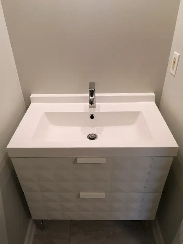 A clean and modern bathroom vanity installation completed as part of a Mississauga interior renovation project. This space features a contemporary white vanity with integrated sink, minimalist chrome faucet, and neutral wall tones, enhancing both functionality and visual balance. Designed and installed by a professional Toronto renovation company, the project focuses on space efficiency, durability, and modern aesthetics suitable for condo and residential interiors.