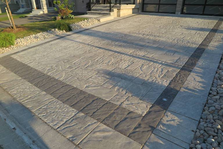 Stamped concrete driveway renovation for a detached home in Vaughan featuring natural stone texture patterns and a contrasting decorative border. This front yard hardscaping design provides a durable, low-maintenance driveway while enhancing the property’s modern curb appeal and overall landscape layout.