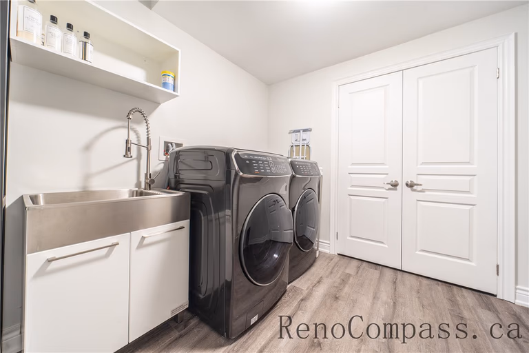 This Richmond Hill entire house interior renovation includes a clean and functional laundry room with modern washer and dryer units, a utility sink, and custom storage cabinetry. Durable flooring, bright lighting, and organized shelving enhance efficiency and everyday convenience. Completed by a professional Toronto renovation company, this laundry room renovation combines practicality, comfort, and contemporary design for improved home functionality.