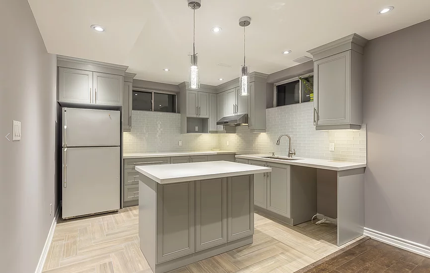 This Toronto basement renovation features a modern custom kitchen with grey shaker cabinets, quartz countertops, a center island, and upgraded lighting. Designed for functionality and style, this basement kitchen includes full cabinetry installation, backsplash tiling, stainless steel appliances, and optimized layout for comfortable living. Completed by a professional Toronto renovation company specializing in basement finishing and interior upgrades.
