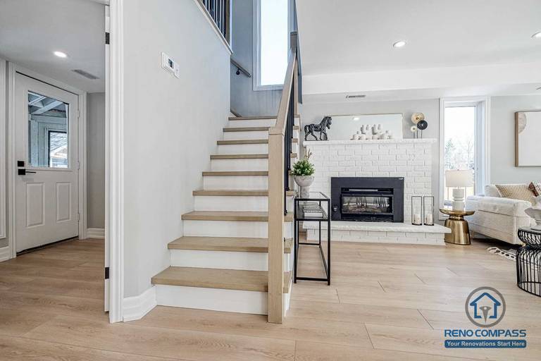 This Georgian interior renovation features a refined staircase design with light wood treads, clean railings, and a clear view toward the living room fireplace. The layout balances classic structure with modern finishes, completed by a Toronto renovation company.