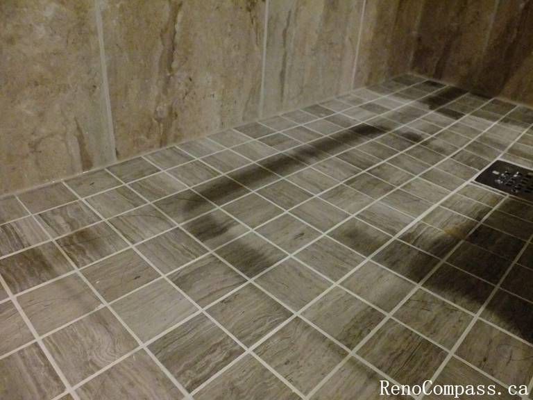 Close-up view of shower floor tile installation from a North York bathroom renovation, highlighting slip-resistant mosaic tiles, proper slope, clean grout lines, and integrated floor drain detailing.