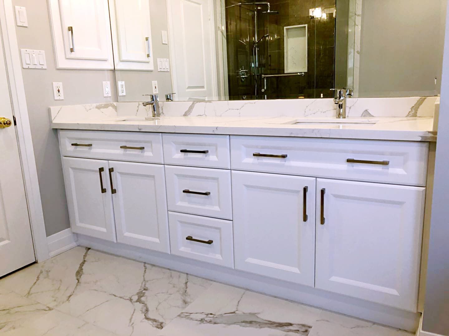 This Richmond Hill bathroom renovation features a modern double-sink vanity with custom white shaker cabinetry, quartz countertops, and sleek black hardware. The upgraded layout improves both storage and daily functionality while maintaining a clean and timeless aesthetic. Large-format marble-style flooring and a glass shower enclosure enhance the luxury feel, creating a bright and elegant space ideal for modern family living. Professionally completed by a trusted Toronto renovation company, this project combines durability, comfort, and refined design for long-term use.