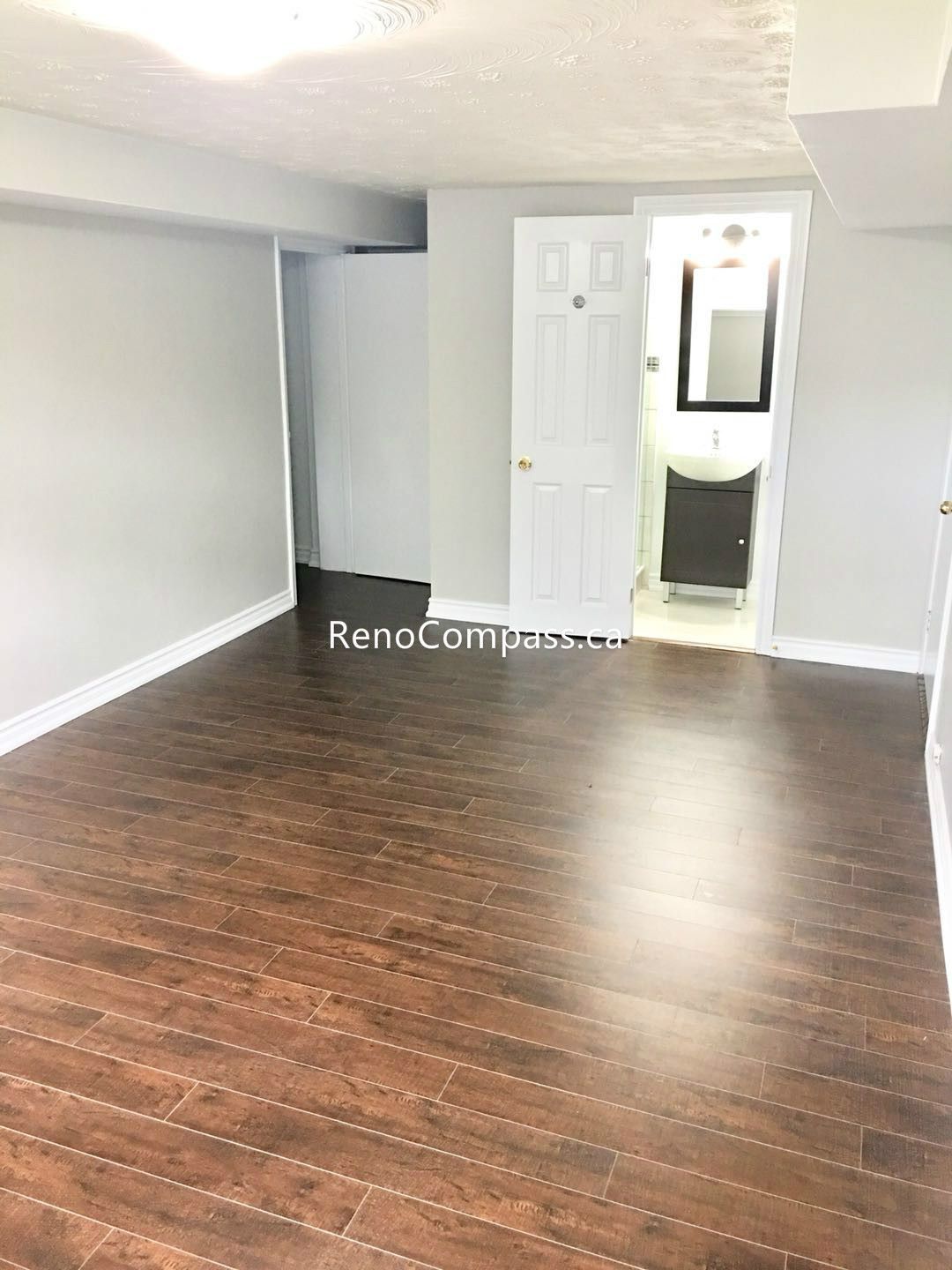 This Toronto basement renovation features a newly finished open living area with modern dark wood flooring and clean neutral wall finishes. The updated layout creates a bright, spacious, and functional basement environment suitable for family use or rental potential. Completed by Reno Compass Inc., this basement renovation enhances comfort, durability, and property value through quality craftsmanship and contemporary design.