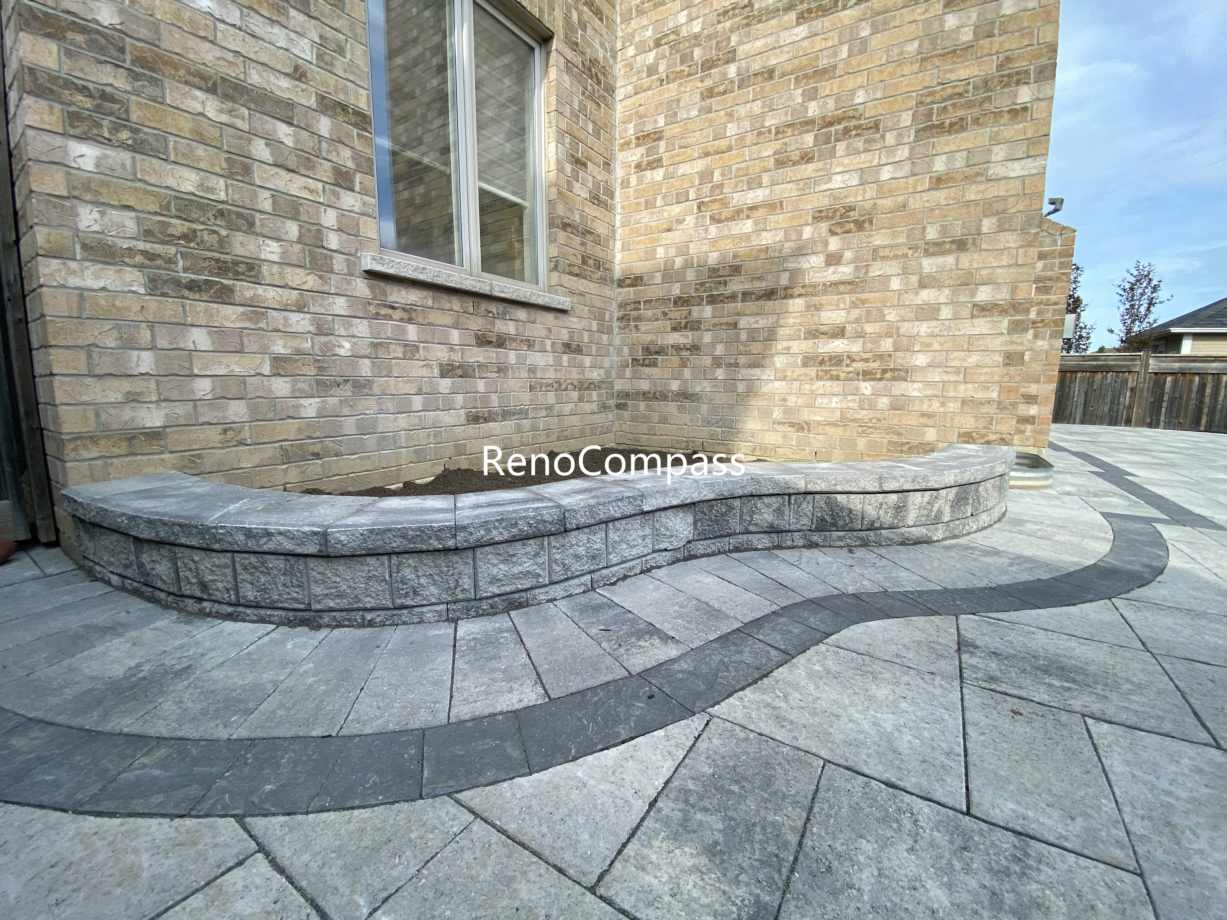 This Aurora interlocking detail showcases a curved retaining wall seamlessly integrated with a decorative paver layout. The rounded wall design adds depth and architectural interest while providing structural support and landscape definition. Large-format concrete pavers with a contrasting curved inlay create smooth visual flow and precise edge alignment. This professionally crafted retaining wall and interlock combination enhances durability, drainage, and aesthetics, offering a refined outdoor solution for residential properties in Aurora.