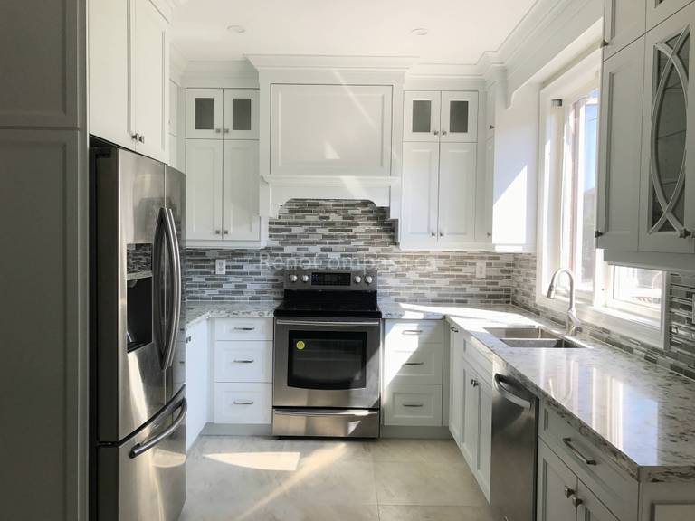 This Markham kitchen renovation project showcases a bright and modern design completed by a professional Toronto Renovation Company. The space features elegant white shaker cabinets, stainless steel appliances, quartz countertops, and a stylish mosaic tile backsplash that adds texture and depth to the kitchen. Large windows bring in natural light, creating a clean and welcoming atmosphere. The layout maximizes storage and functionality while maintaining a timeless aesthetic suitable for modern family living.