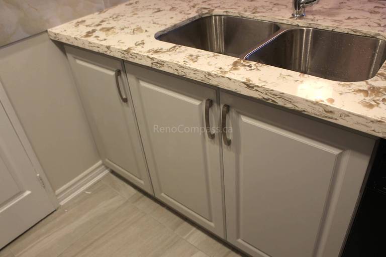 Modern kitchen renovation in Mississauga featuring a premium quartz countertop, double stainless steel sink, and contemporary pull-down faucet. The upgraded cabinetry and marble-style backsplash enhance both functionality and visual appeal. Completed by Reno Compass, a trusted Toronto renovation company, this project showcases practical and stylish kitchen interior upgrades for homeowners across the GTA.