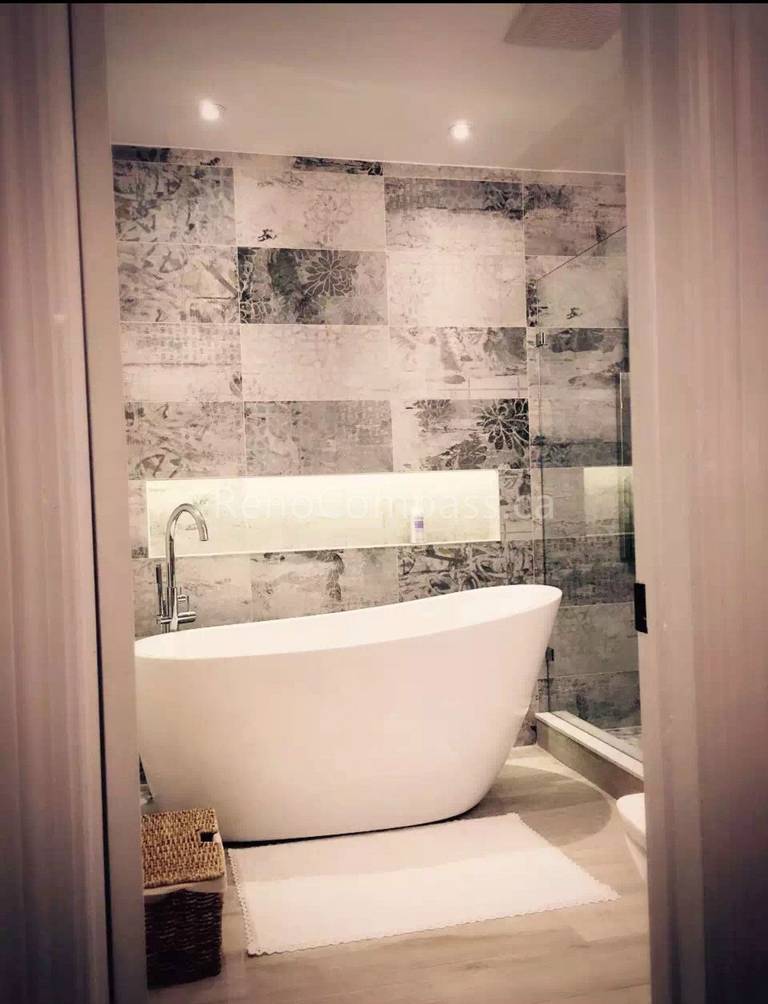 A modern bathroom interior renovation in Toronto featuring a freestanding soaking bathtub, textured tile accent wall, recessed lighting, and warm wood flooring. This interior design emphasizes clean lines, spa-inspired comfort, and contemporary finishes, showcasing professional Toronto interior design and renovation craftsmanship.