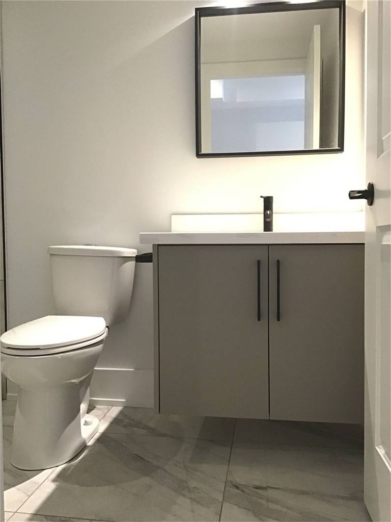 This Markham full home renovation features a compact and modern powder room with a sleek vanity, clean-lined mirror, and durable tile flooring. The neutral color palette and matte black fixtures create a simple yet elegant space, maximizing functionality in a smaller layout. Completed by a trusted Toronto Renovation Company, this design reflects efficient use of space with contemporary style.