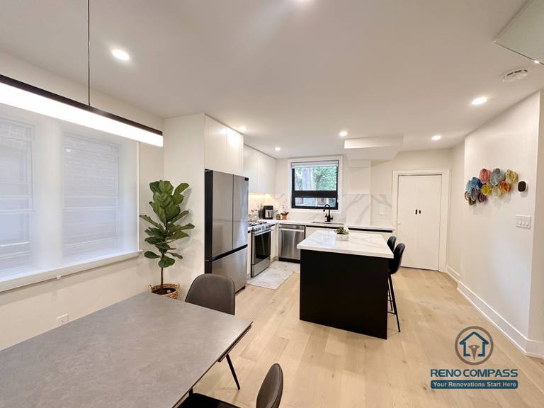 This Toronto interior renovation features a cohesive kitchen and dining area with a central island, quartz countertops, flat-panel cabinetry, stainless steel appliances, and warm wide-plank hardwood flooring. The open layout enhances everyday functionality and visual balance, showcasing thoughtful design and execution by a trusted Toronto renovation company.