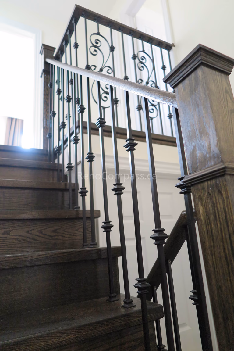 This image highlights a North York flooring renovation featuring a hardwood staircase paired with custom wrought iron railings. The dark wood stair treads create a strong visual connection with the surrounding flooring, while the iron balusters add structure, safety, and timeless elegance. As an experienced Toronto Renovation Company, Reno Compass Inc. delivers cohesive flooring and stair solutions that balance durability, craftsmanship, and refined interior design for residential homes.
