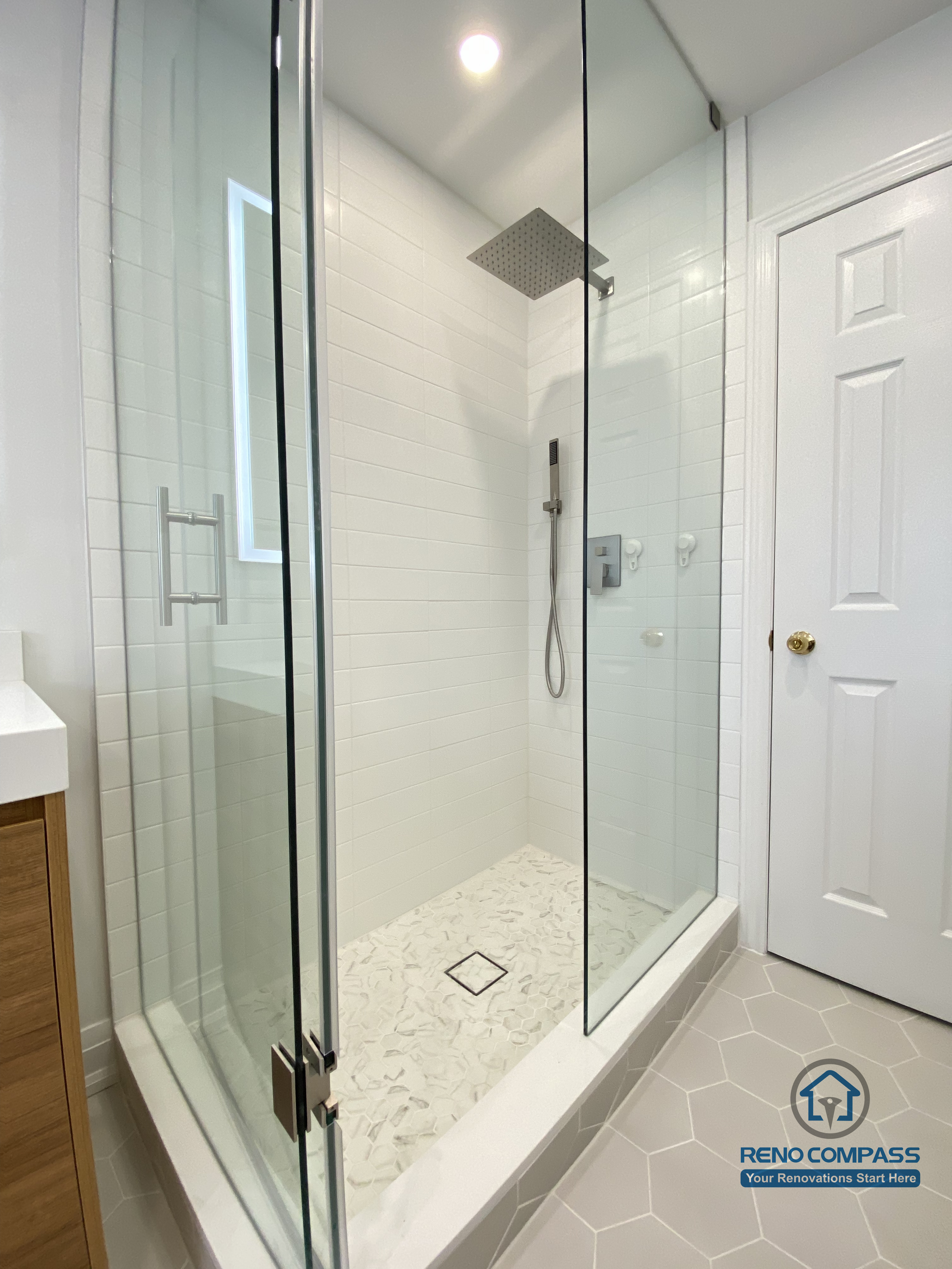 This Markham bathroom renovation highlights a custom double sink vanity designed to improve daily efficiency and long-term usability. The wood-tone vanity provides ample concealed storage while adding warmth and visual balance to the space. A full-width LED backlit mirror delivers even, glare-free lighting, enhancing functionality for everyday routines. Slip-resistant hexagon tile flooring improves safety and durability in a high-moisture environment, while neutral wall tones maintain a clean, timeless appearance. Completed by a Toronto renovation company, Reno Compass Inc., this bathroom renovation reflects careful space planning, material coordination, and a modern, practical design approach for Markham homes.