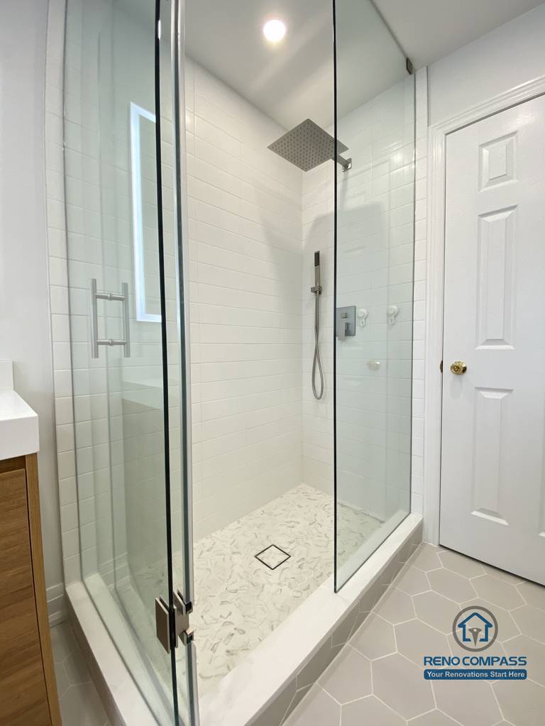 This Markham bathroom renovation highlights a custom double sink vanity designed to improve daily efficiency and long-term usability. The wood-tone vanity provides ample concealed storage while adding warmth and visual balance to the space. A full-width LED backlit mirror delivers even, glare-free lighting, enhancing functionality for everyday routines. Slip-resistant hexagon tile flooring improves safety and durability in a high-moisture environment, while neutral wall tones maintain a clean, timeless appearance. Completed by a Toronto renovation company, Reno Compass Inc., this bathroom renovation reflects careful space planning, material coordination, and a modern, practical design approach for Markham homes.