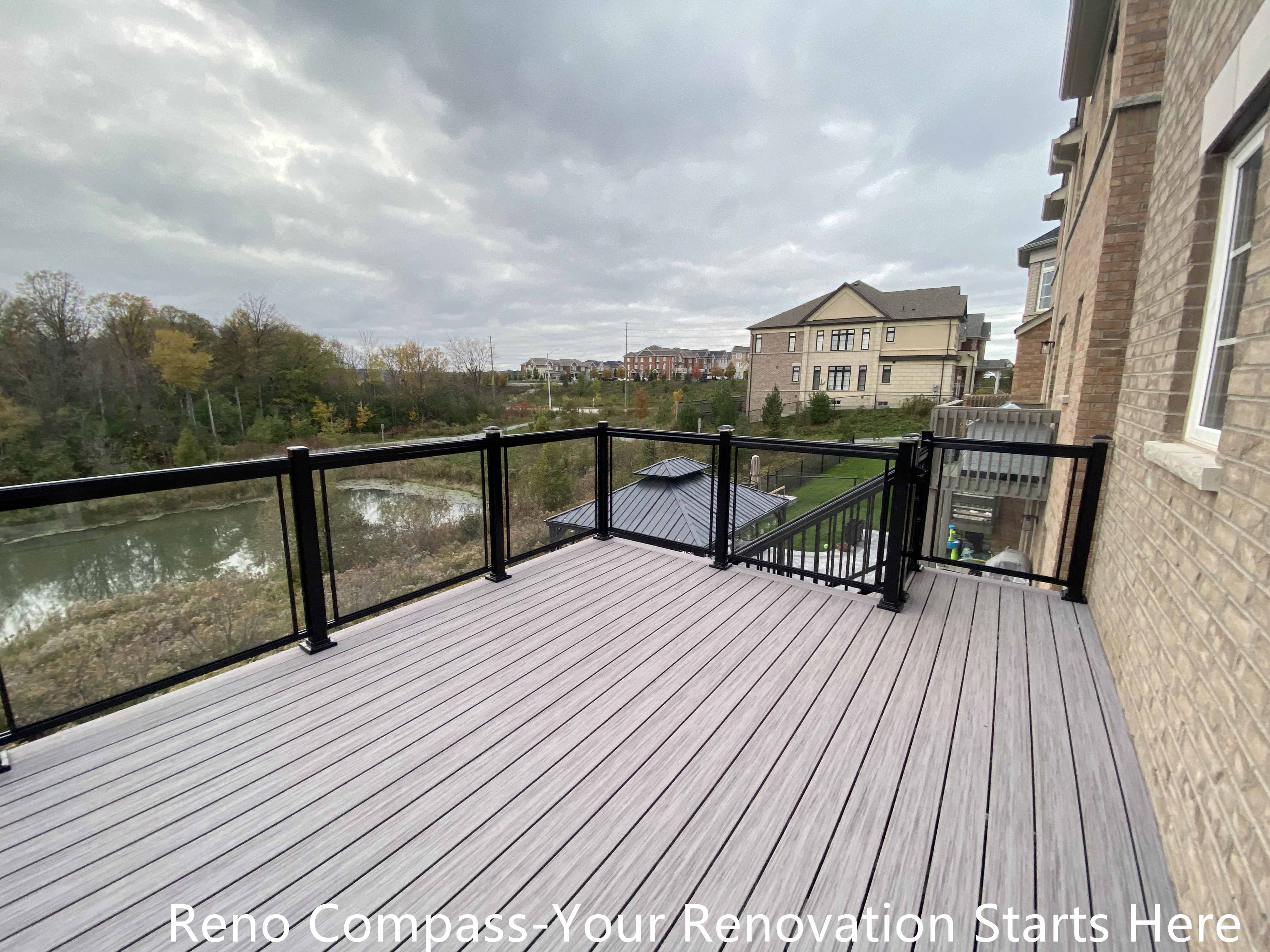 Modern Aurora deck featuring durable wooden flooring and sleek glass railings, designed for outdoor leisure, family gatherings, and seamless integration with the home exterior. Project by Reno Compass Inc.