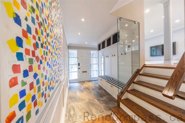 This foyer and staircase area is part of a North York interior renovation, designed to create a welcoming and highly functional entrance. The space features custom glass-front closet doors, built-in storage, and warm hardwood stairs that add depth and durability. Recessed ceiling lighting enhances brightness, while large entry windows bring in natural light. Clean lines, practical circulation flow, and quality material selection reflect the craftsmanship and thoughtful planning of professional Toronto interior renovation projects.