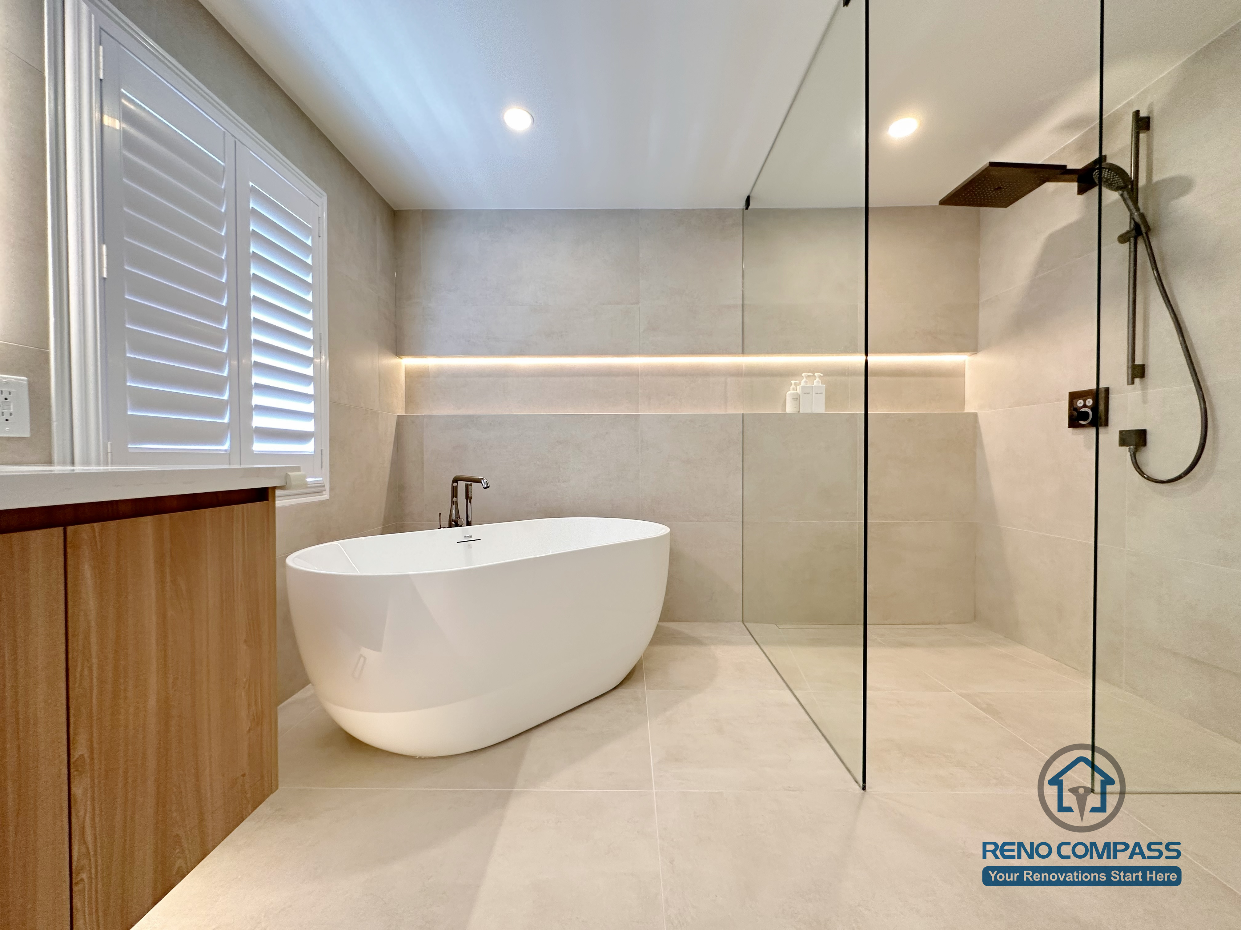 This Markham accessible bathroom renovation features a freestanding bathtub positioned within a barrier-free layout, allowing easy movement and step-free access. Large-format floor and wall tiles, integrated linear lighting, and a custom wood-tone vanity contribute to a calm, safe, and modern environment. Designed and built by a professional Toronto renovation company, Reno Compass Inc., the space prioritizes accessibility, comfort, and long-term usability.