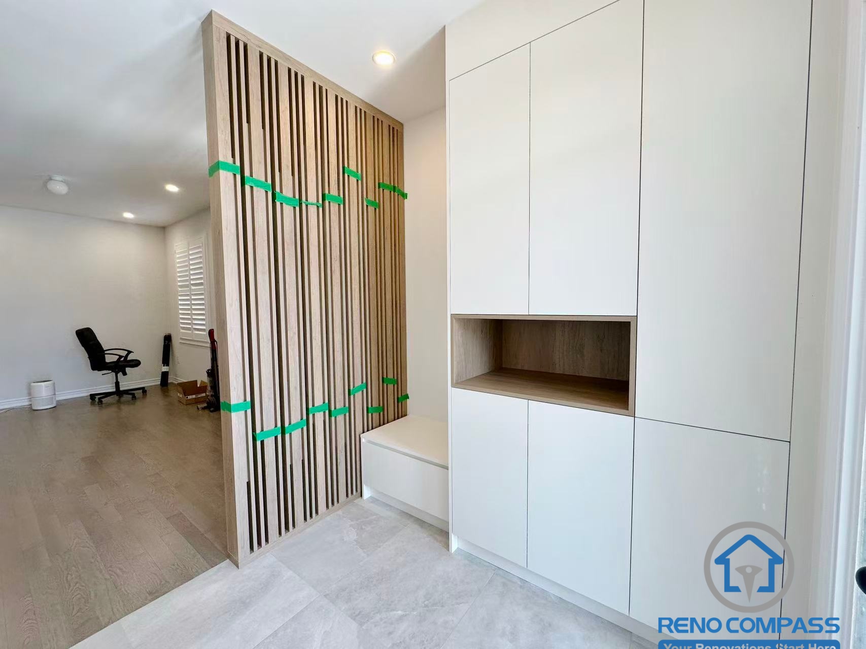 This Stouffville interior renovation features a custom wood slat divider paired with built-in entryway cabinetry, creating a functional separation between the foyer and living space while maintaining visual openness. The combination of warm wood tones and clean white finishes enhances both privacy and flow. Completed by a professional Toronto renovation company, Reno Compass Inc., this project highlights custom millwork and thoughtful interior space planning.