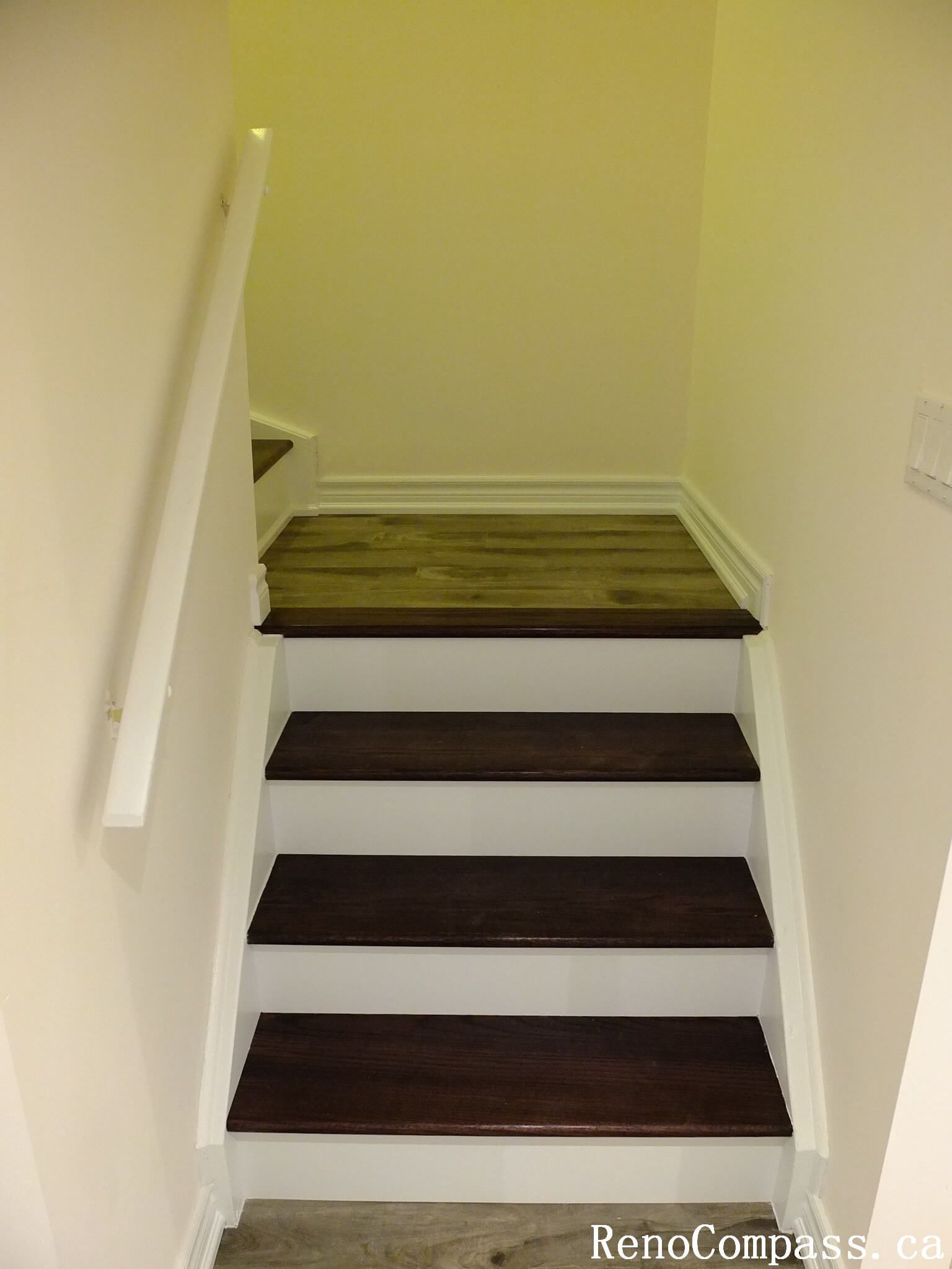 This Markham basement renovation showcases newly finished basement stairs featuring rich wood treads, white risers, and a clean modern handrail. The upgraded staircase enhances safety, durability, and visual continuity, seamlessly connecting the main floor to the newly renovated basement space.