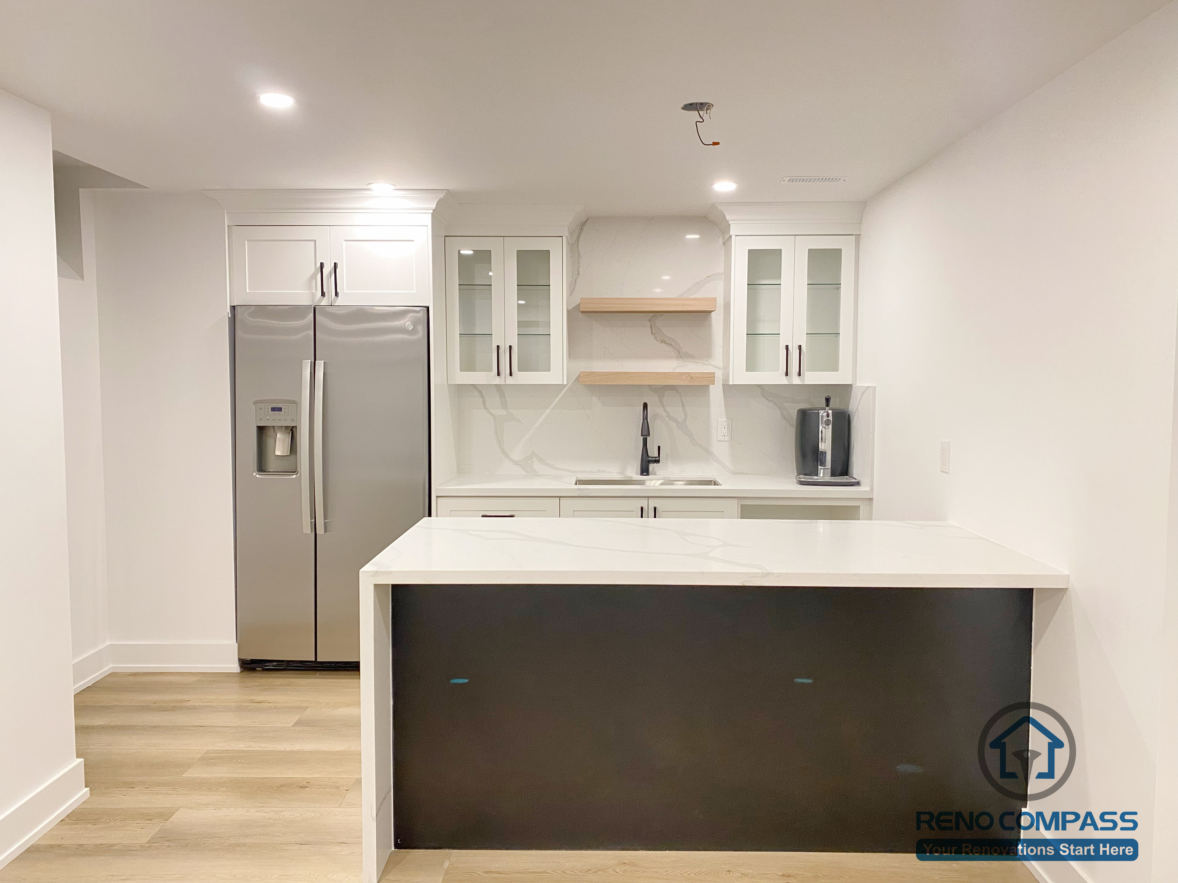 This modern basement kitchen includes a functional island layout, clean cabinetry, and efficient lighting. Designed to support entertaining and everyday use, the space seamlessly connects with the surrounding basement living areas.