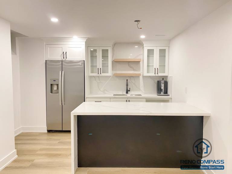 This modern basement kitchen includes a functional island layout, clean cabinetry, and efficient lighting. Designed to support entertaining and everyday use, the space seamlessly connects with the surrounding basement living areas.