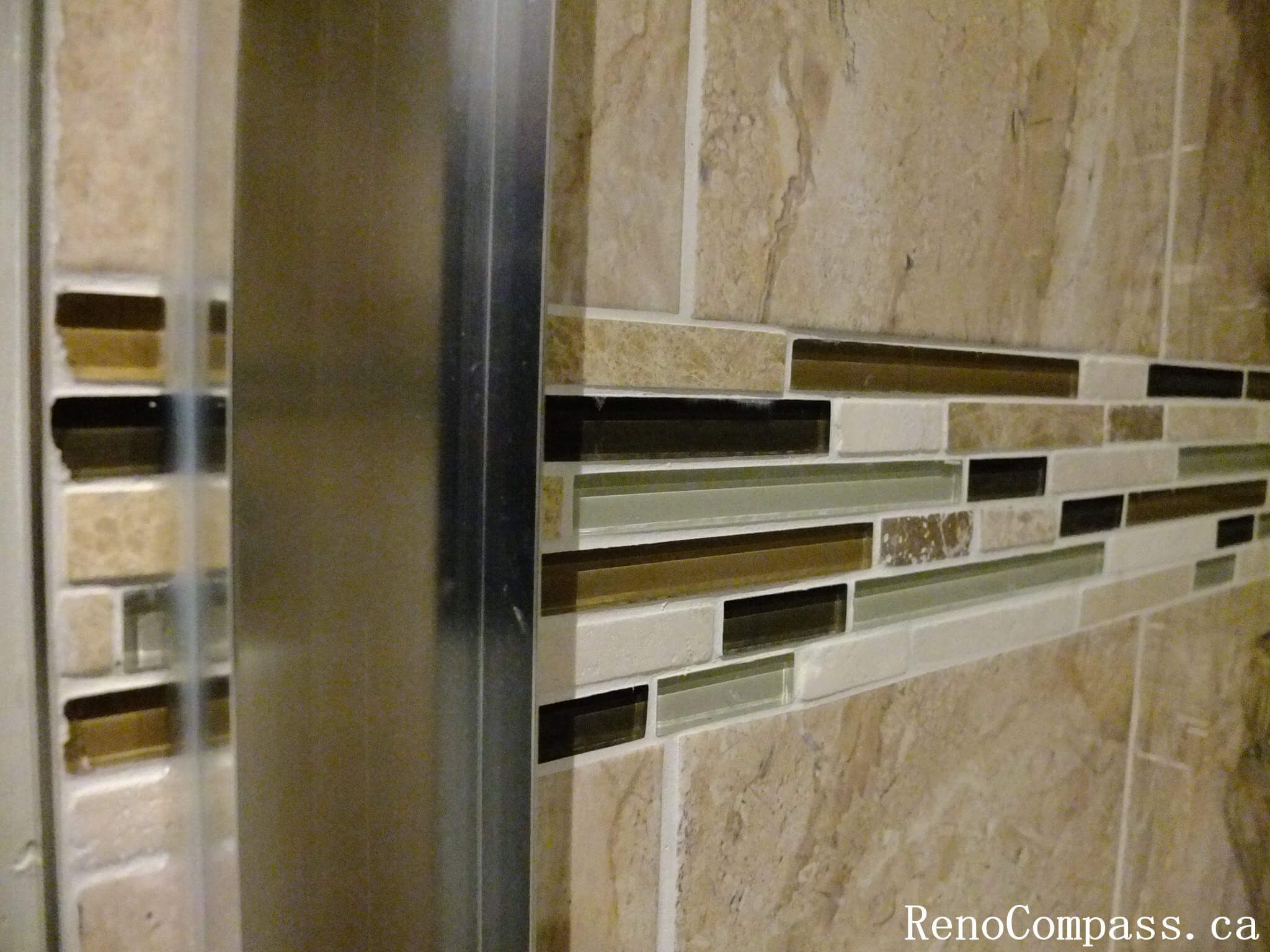 Accent tile detail from a North York bathroom renovation, featuring a horizontal glass mosaic band integrated with wall tiles for added depth, texture, and a refined shower design.
