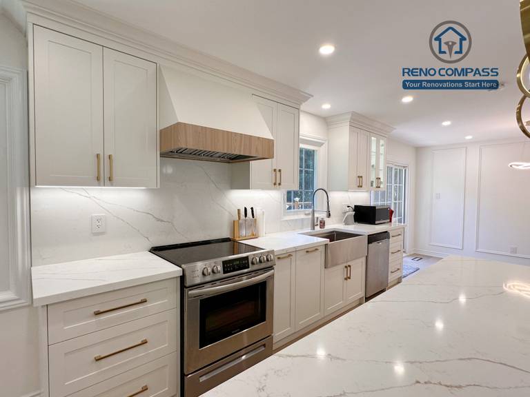 This Markham kitchen renovation showcases custom white cabinetry with brass hardware, quartz countertops, and a fully integrated appliance wall featuring a stainless steel range and farmhouse-style sink. Under-cabinet lighting and a clean backsplash enhance both functionality and visual clarity. Completed by a professional Toronto renovation company, Reno Compass Inc., the design emphasizes practicality, refined detailing, and long-term performance.
