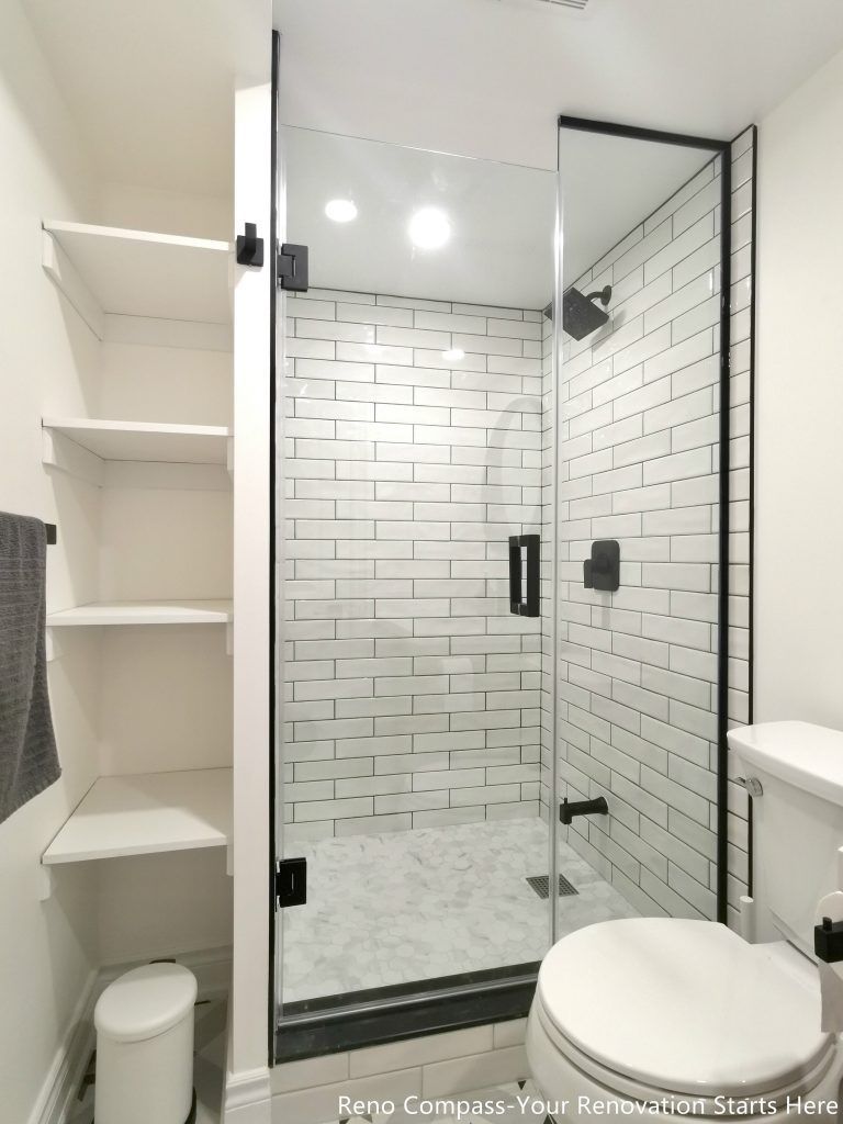 This image showcases a walk-in shower area from a completed basement renovation in Vaughan, featuring classic white subway tile walls, a frameless glass enclosure, and matte black shower fixtures. Built-in open shelving provides practical storage for everyday use, helping maintain a clean and organized bathroom layout. The combination of moisture-resistant materials, precise tile installation, and efficient space planning enhances both durability and functionality. This basement bathroom renovation reflects the attention to detail and craftsmanship delivered by a professional Toronto renovation company specializing in high-quality basement upgrades.