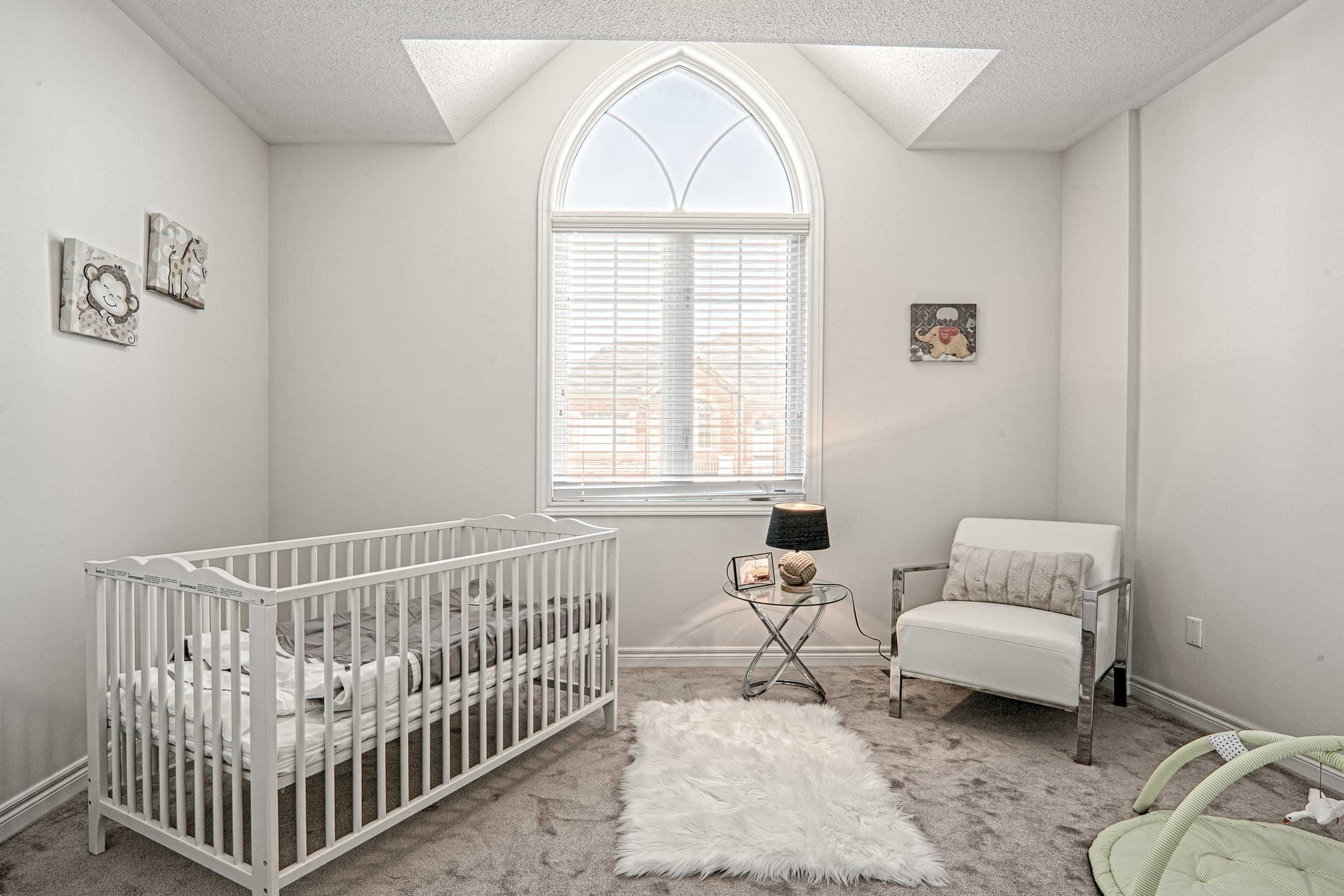 This Toronto nursery room renovation features a bright and cozy kids bedroom with a high ceiling and elegant arched window that fills the space with natural light. The design includes soft neutral tones, premium carpeting, and a functional layout that creates a warm and comfortable environment for a growing family. Completed by a professional Toronto renovation company, this residential interior project highlights thoughtful space planning, modern finishes, and family-friendly design for contemporary living.