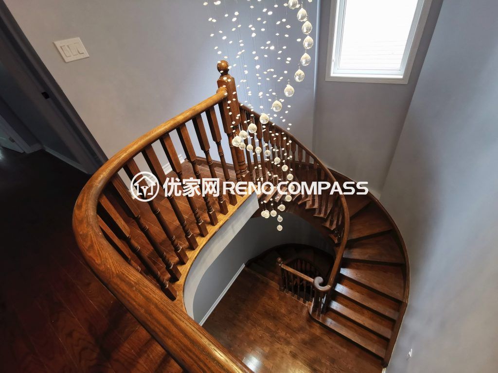 Richmond Hill interior renovation featuring a curved solid wood staircase with custom railings and a modern cascading chandelier. The upgraded stairwell design enhances natural light, architectural elegance, and overall home value, completed by a professional Toronto renovation company.