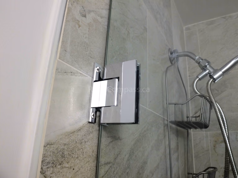 This North York bathroom renovation features a sleek glass shower door with a polished chrome handle and upgraded shower fixtures set against full-height marble-look tile walls. Completed by a professional Toronto renovation company, the project highlights precision installation, durable materials, and modern design details that enhance both functionality and overall bathroom aesthetics.