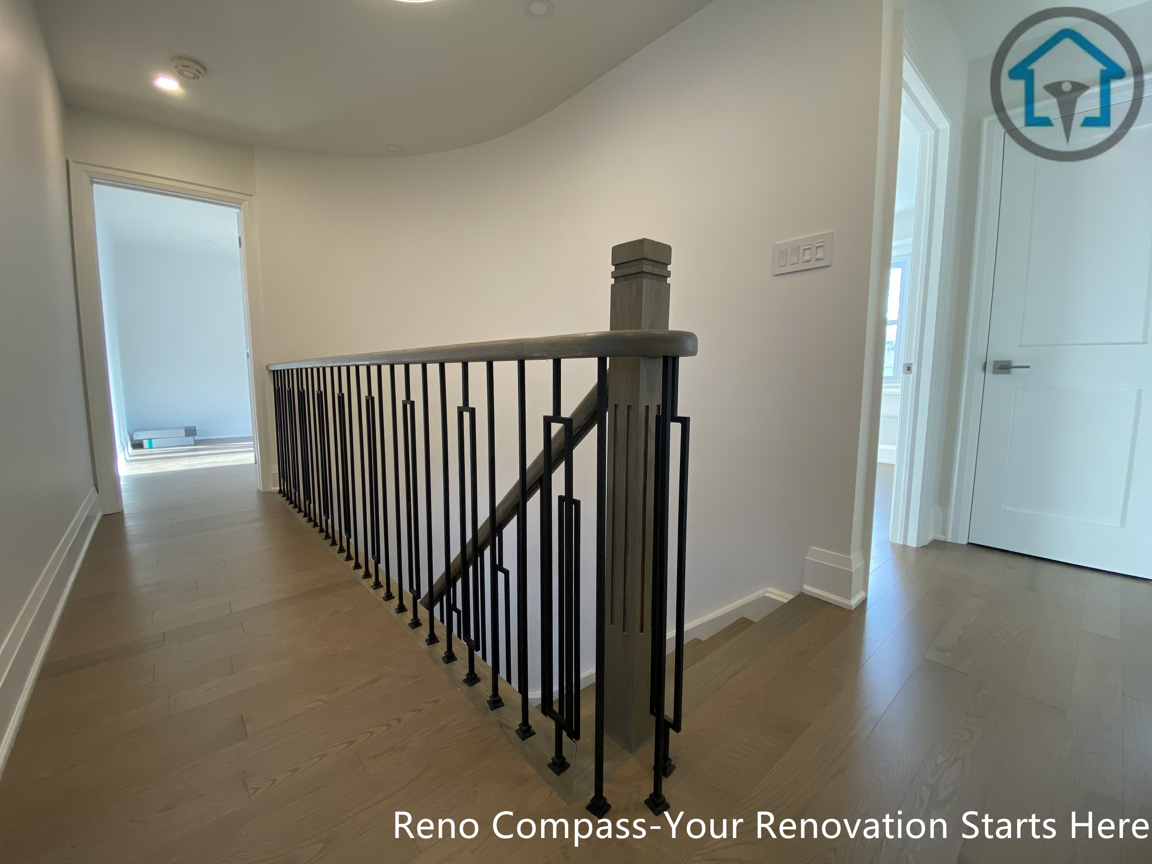 This image showcases a staircase renovation in Markham featuring a modern black metal railing paired with light hardwood flooring. Completed by Toronto Renovation Company Reno Compass Inc., the design enhances safety while maintaining a clean, contemporary look.