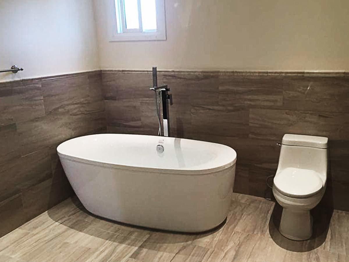 This modern bathroom renovation by Reno Compass features a sleek freestanding bathtub, contemporary floor-mounted faucet, and warm wood-tone wall tiles for a spa-like atmosphere. Designed with both comfort and functionality in mind, the layout maximizes space while maintaining a clean and elegant look. As a professional Toronto renovation contractor, Reno Compass delivers high-quality bathroom remodeling with attention to detail, durable materials, and modern design aesthetics for homeowners across the GTA.
