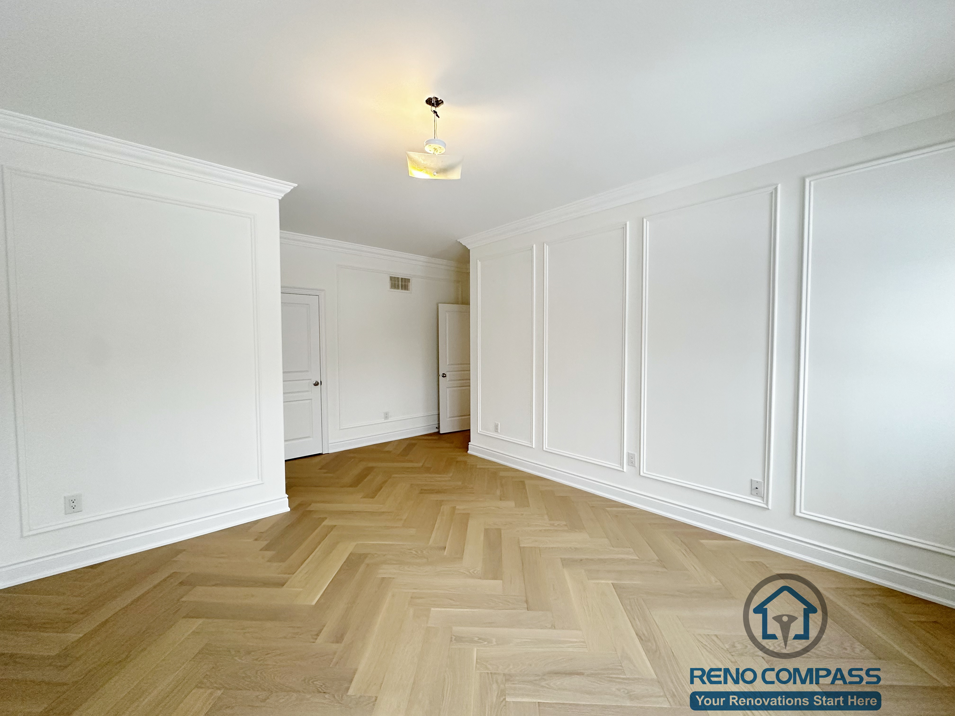 Refined hallway completed as part of a Vaughan interior renovation, featuring custom wall paneling, crown moulding, clean white finishes, and herringbone-pattern hardwood flooring. The balanced proportions and seamless detailing highlight the craftsmanship of a professional Toronto renovation company.
