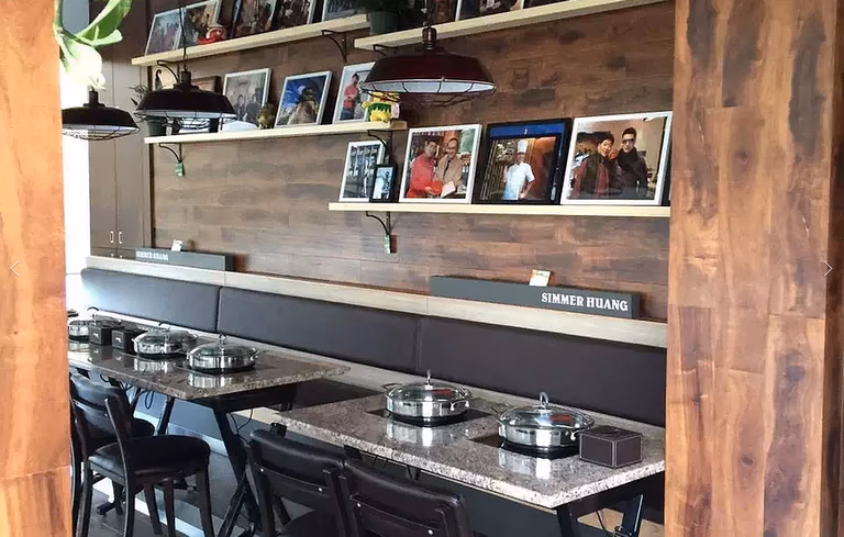 This Markham restaurant renovation by Reno Compass Inc. features a stylish dining wall with custom wood paneling, floating display shelves, and warm pendant lighting. The seating area is designed with durable stone-top tables and comfortable bench seating to enhance both aesthetics and functionality. Decorative photo displays and modern finishes create a welcoming and personalized dining environment, reflecting thoughtful commercial interior design and quality craftsmanship.