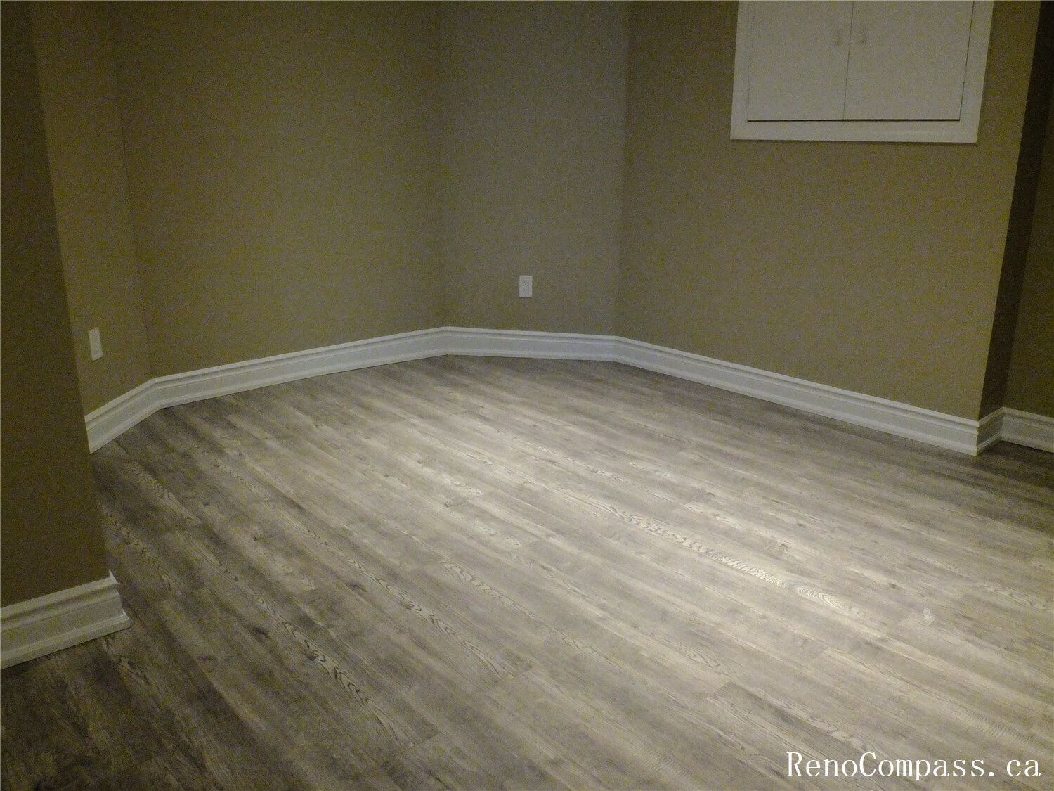 View of a finished basement room in this Ajax basement renovation, featuring durable vinyl plank flooring, neutral wall tones, and recessed pot lights for bright, even lighting. The clean layout and modern finishes make this space ideal for a home office, guest room, or recreation area. Completed by a professional Toronto Renovation Company, the renovation focuses on comfort, functionality, and long-lasting materials suitable for basement living spaces.