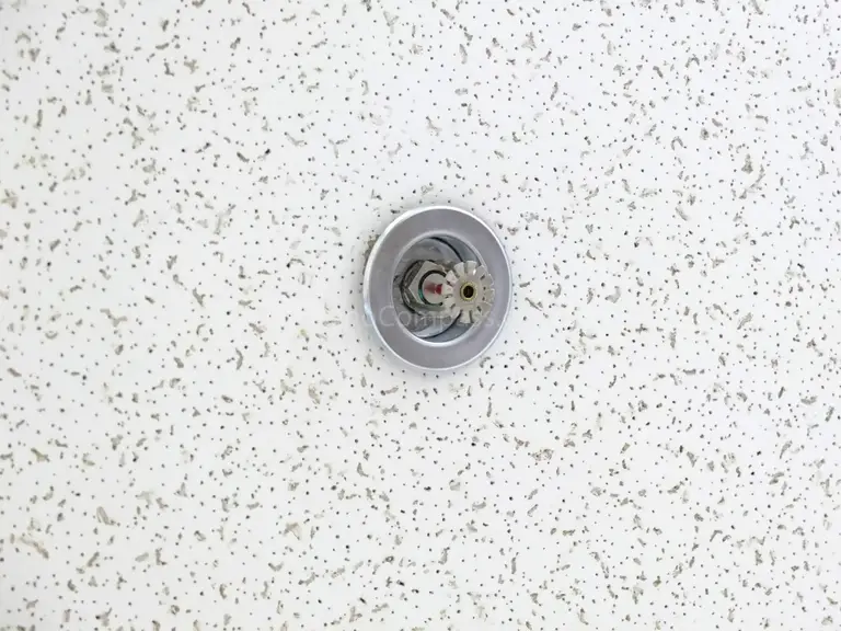 This close-up photo shows a ceiling-mounted fire sprinkler head installed within acoustic ceiling panels during a North York office renovation project. The sprinkler system enhances workplace safety and ensures compliance with modern fire protection standards.